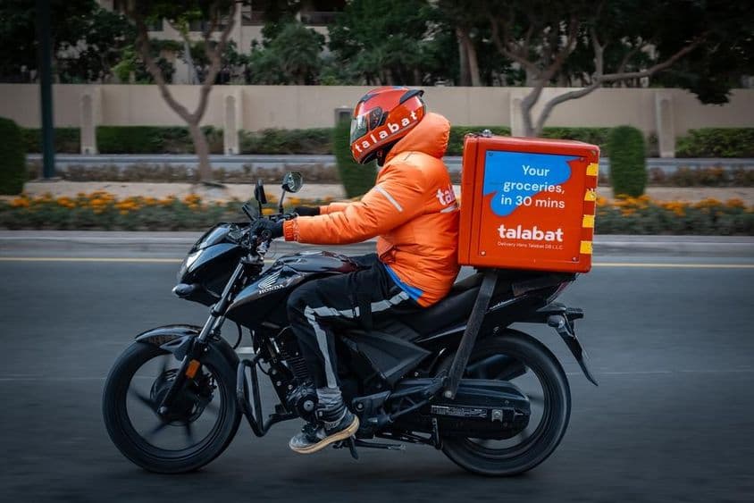 Motocycliste livrant de la nourriture, navigant dans les rues animées de Dubaï.