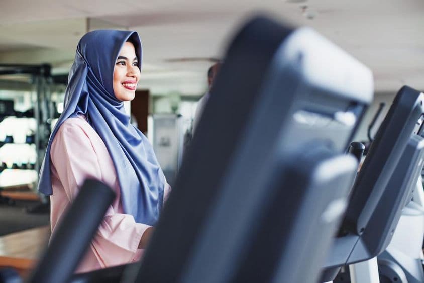 Femme musulmane s'exerce dans une salle de sport, portant un hijab.