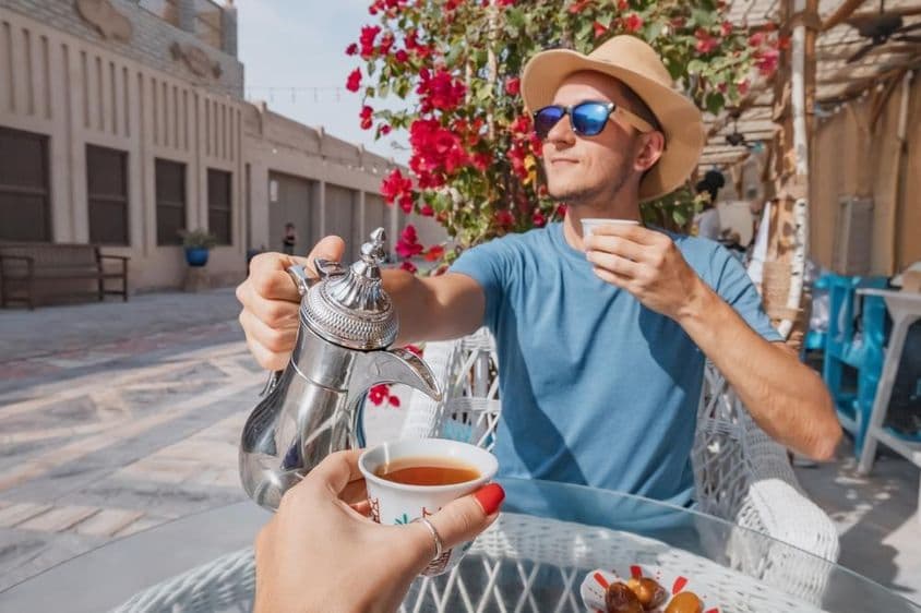 Un homme à Dubaï se reposant dans un café arabe, versant du café aromatique d'une cafetière dallah.