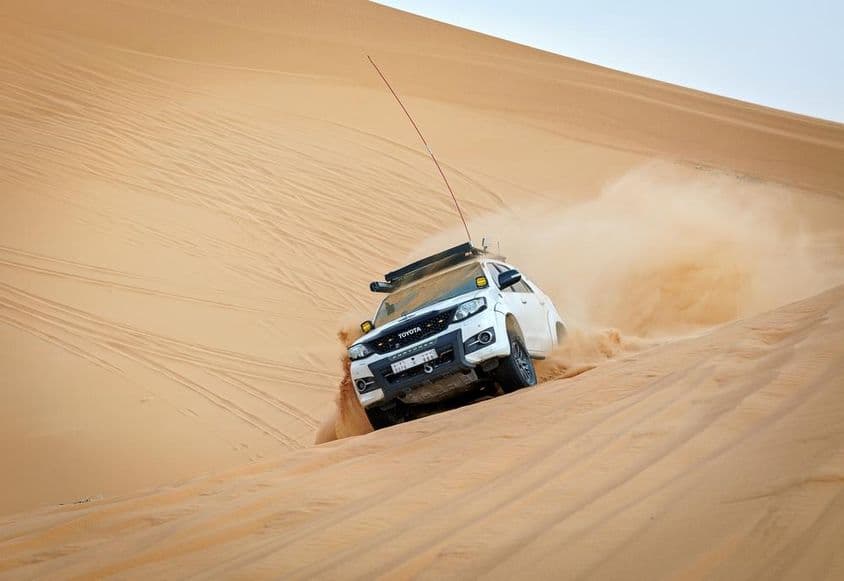 Véhicule 4x4 en course sur une dune.
