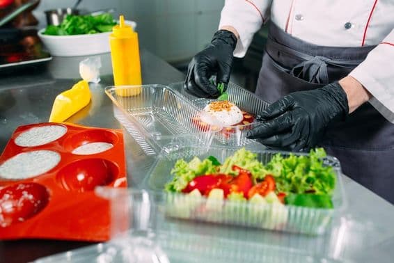 Le chef prépare de la nourriture dans le restaurant et l'emballe dans des contenants jetables.