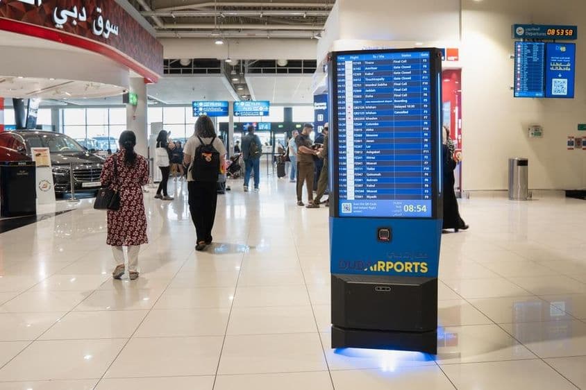 Intérieur de l'aéroport de Dubaï avec un panneau d'information.