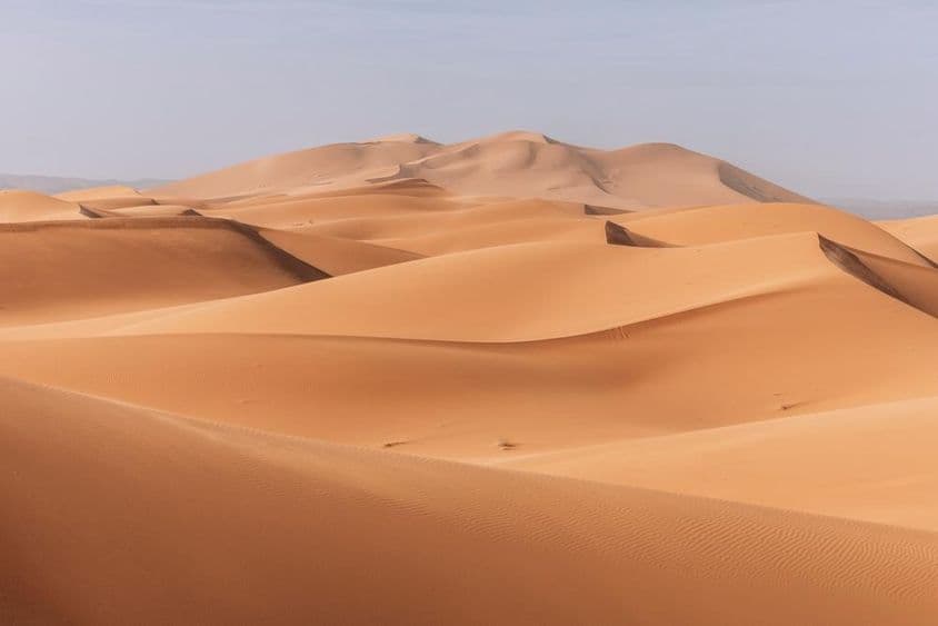 Dunes imposantes, coucher de soleil doré sur un paysage calme et silencieux.