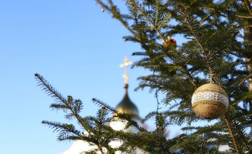 Branche d'un sapin de Noël avec des ornements, avec une croix orthodoxe en arrière-plan