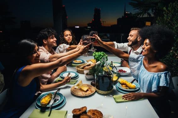 Groupe d'amis savourant un repas et célébrant sur un magnifique balcon en penthouse.