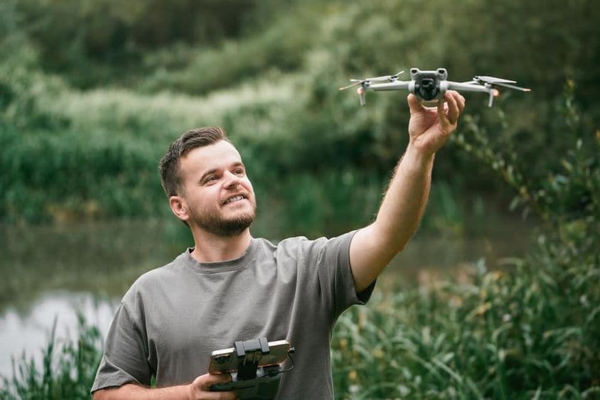 Instructeur de drones avec un drone en main lors d'un cours en extérieur.