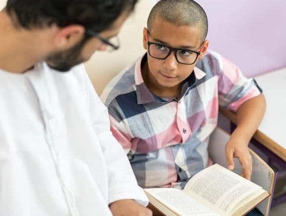 Jeune enseignant arabe étudiant avec un écolier.