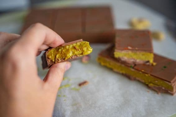 Morceau de chocolat de Dubaï avec pistache et pâtisserie kataifi dans la main d'une femme.