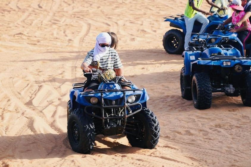 Jeune couple conduisant un quad dans le désert de Dubaï.