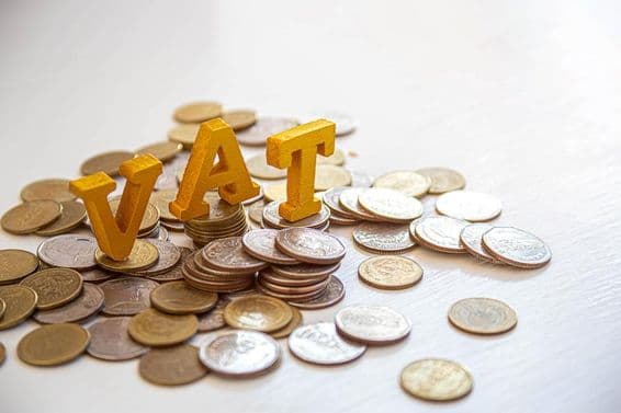 Pièces sur une table avec les lettres "Tax" au-dessus.