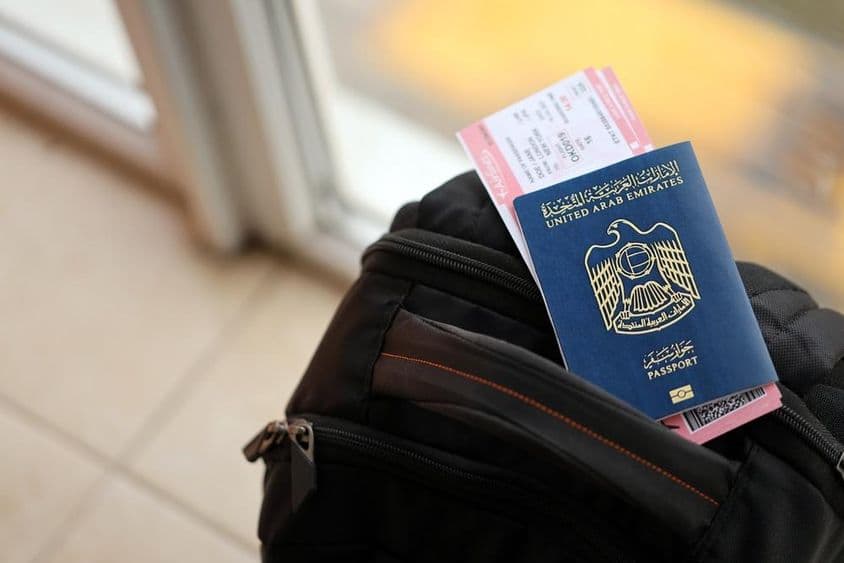 Passeport bleu des Émirats Arabes Unis avec des billets d'avion sur un sac à dos en gros plan.