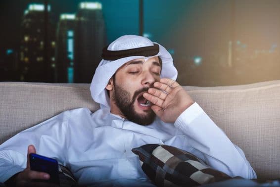 Homme arabe bâillant en regardant la télévision.