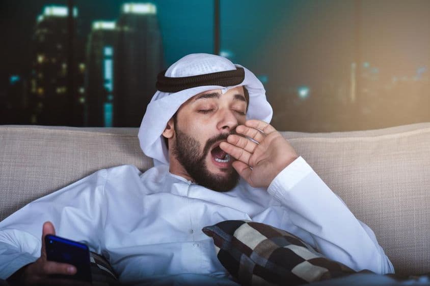 Homme arabe bâillant en regardant la télévision.
