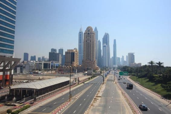 Vue de rue à Dubaï avec gratte-ciels et tramway en arrière-plan.