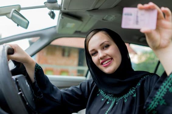 Femme musulmane conduisant une voiture, tenant un permis.