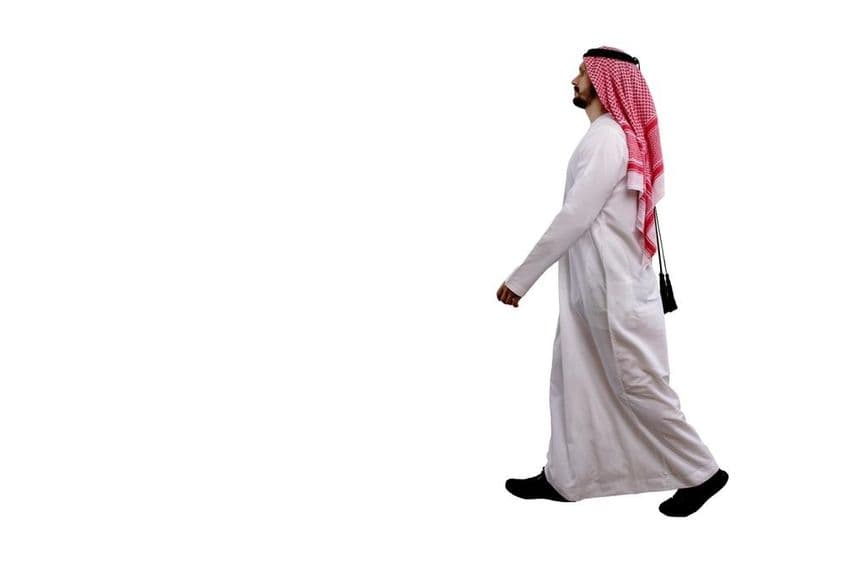 Homme arabe marchant en tenue traditionnelle.