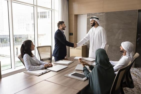 Hommes d'affaires arabes et européens se serrant la main lors d'une réunion d'équipe, discussion professionnelle.