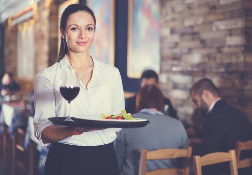 Serveuse souriante tenant un plateau pour les clients du restaurant.
