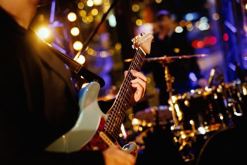 Un guitariste jouant un accord sur le manche pendant une performance du groupe.