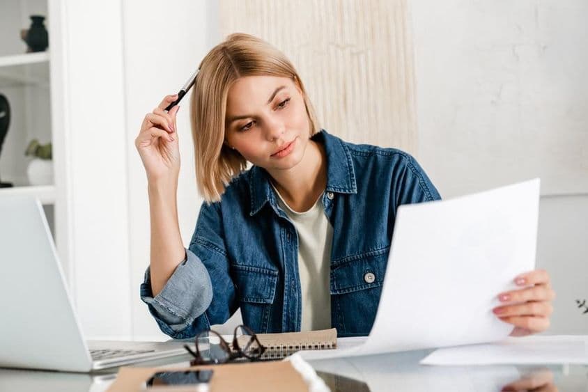 Indépendant pensif préparant ses impôts sur un ordinateur portable.