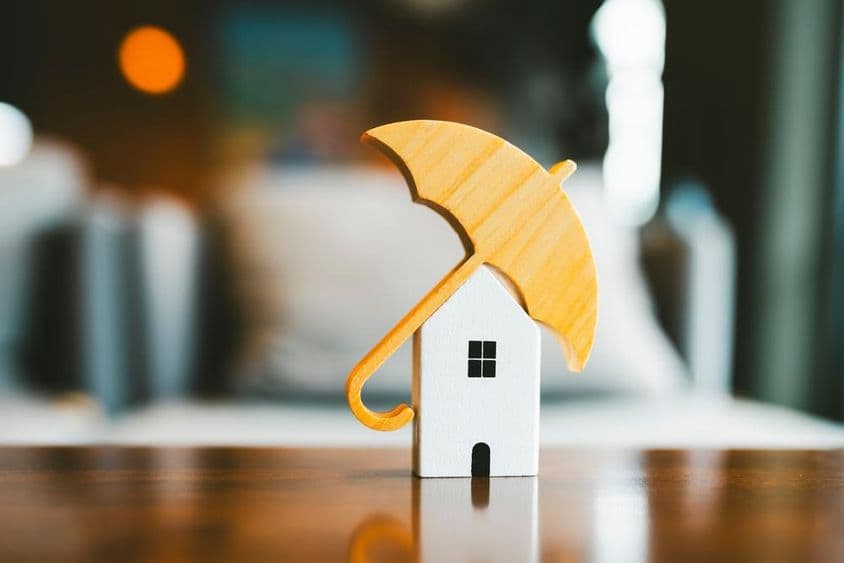 Modèle de parapluie sur une maison en bois, assurance habitation.