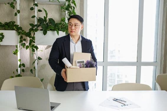 Un homme se fait licencier de son lieu de travail, emballant ses affaires personnelles dans un carton.