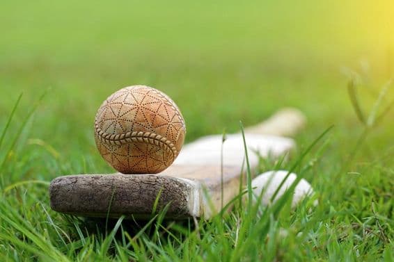 Balle de cricket blanche et batte de cricket sur l'herbe.
