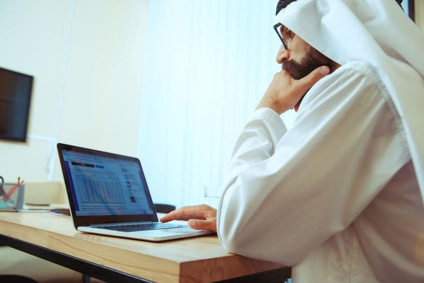 Homme d'affaires arabe travaillant en ligne dans un bureau confortable.