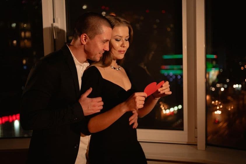 Couple amoureux lors d'un rendez-vous de Saint-Valentin, debout près de la fenêtre.