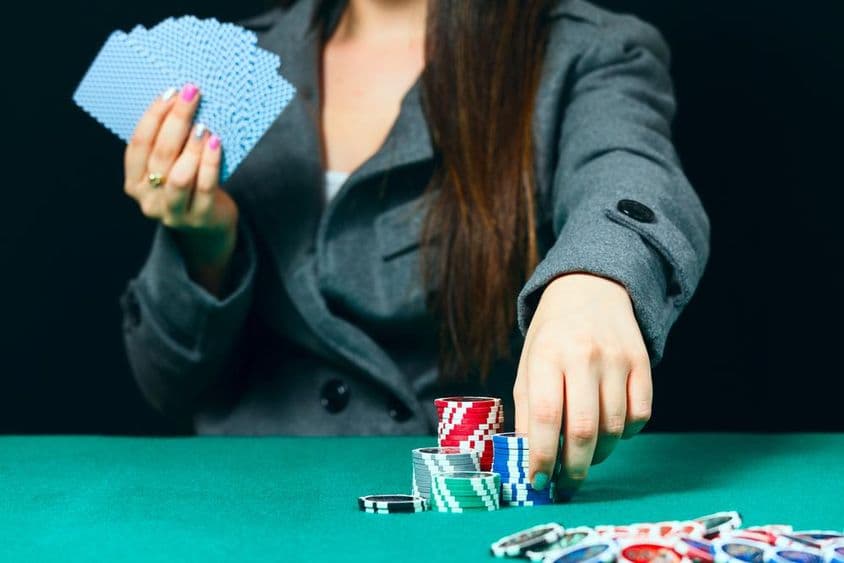 Blackjack dans un casino, une femme place une mise avec des jetons.