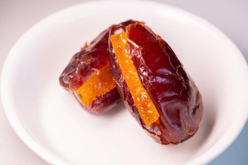 Deux superbes dattes fraîches de Dubaï avec des morceaux d'orange sucrée.