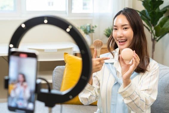 Une jeune influenceuse femme blogueuse utilisant un smartphone, parlant dans un podcast en vidéo streaming.