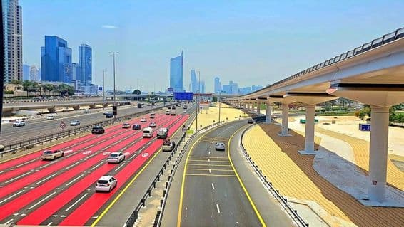 À Dubaï, la route est peinte en rouge avec des marquages de voie blancs et des panneaux de limitation de vitesse indiquant 100 km/h.