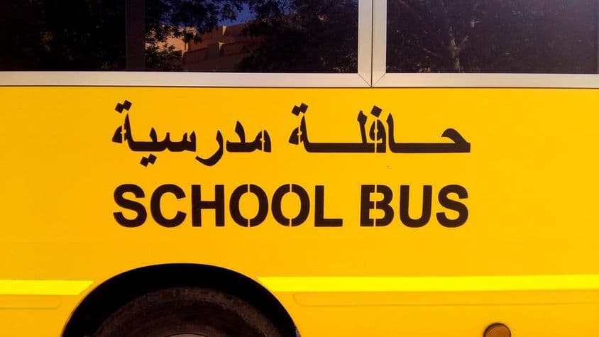 Bus scolaire à Dubaï avec texte en arabe.