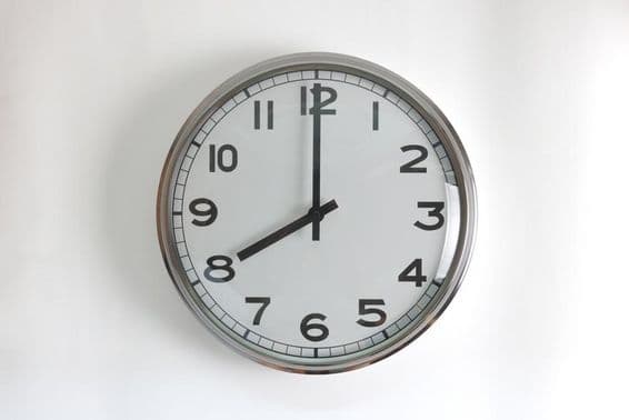 Horloge murale ronde en acier inoxydable avec cadran blanc.