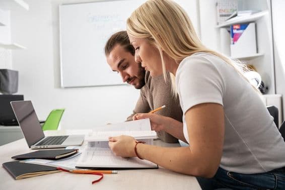 Deux étudiants lisant des supports de cours dans un cahier.