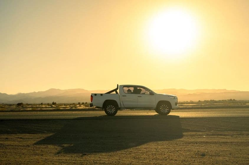 Véhicule pickup blanc en excursion à la campagne, journée ensoleillée au coucher du soleil.