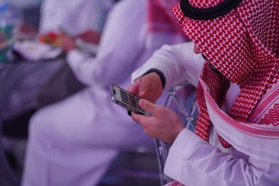 Homme arabe travaillant sur un téléphone mobile, lisant ou tapant un message.
