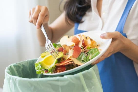 Compost à partir de déchets alimentaires, une jeune gouvernante racle les déchets avec une fourchette.