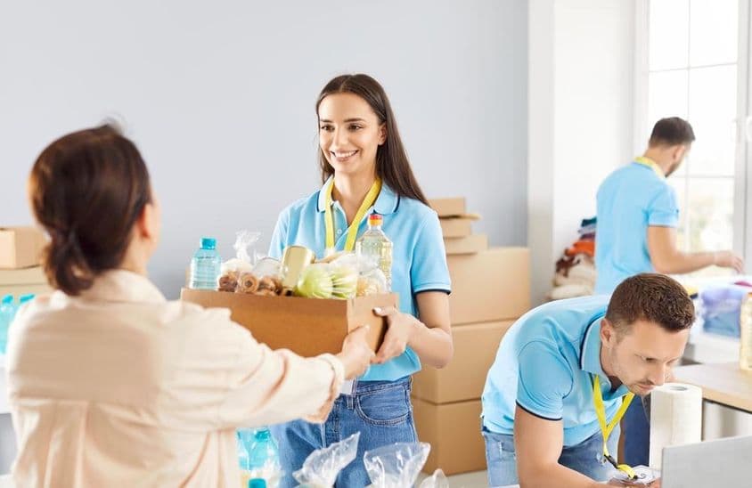 Jeune bénévole distribuant des boîtes de dons alimentaires gratuites à ceux dans le besoin dans une fondation caritative.