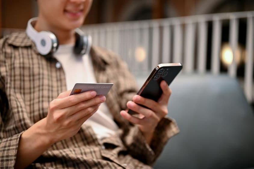 Un homme asiatique utilisant un service de paiement par carte de crédit sur une application de shopping en ligne.