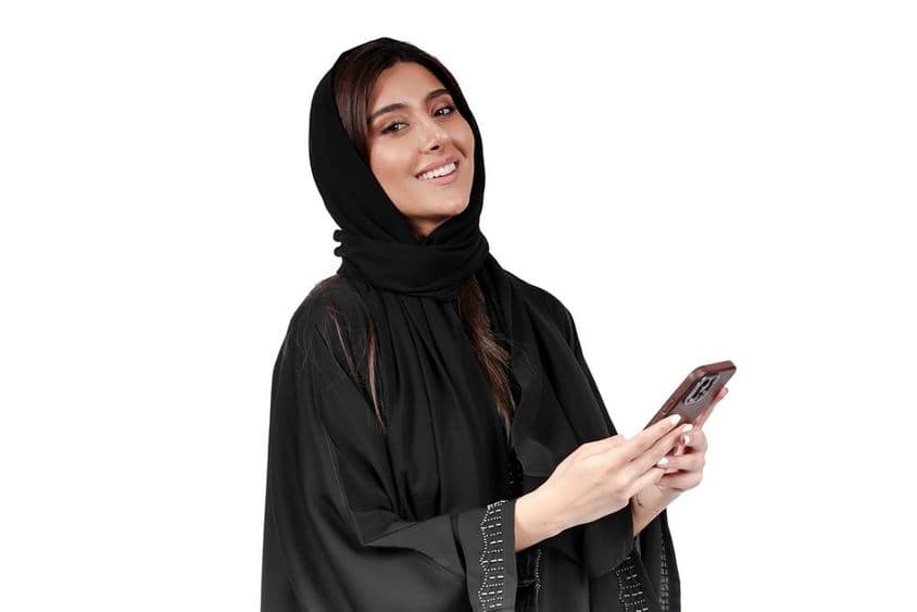 Femme d'affaires émiratie en abaya arabe travaillant sur un téléphone mobile.