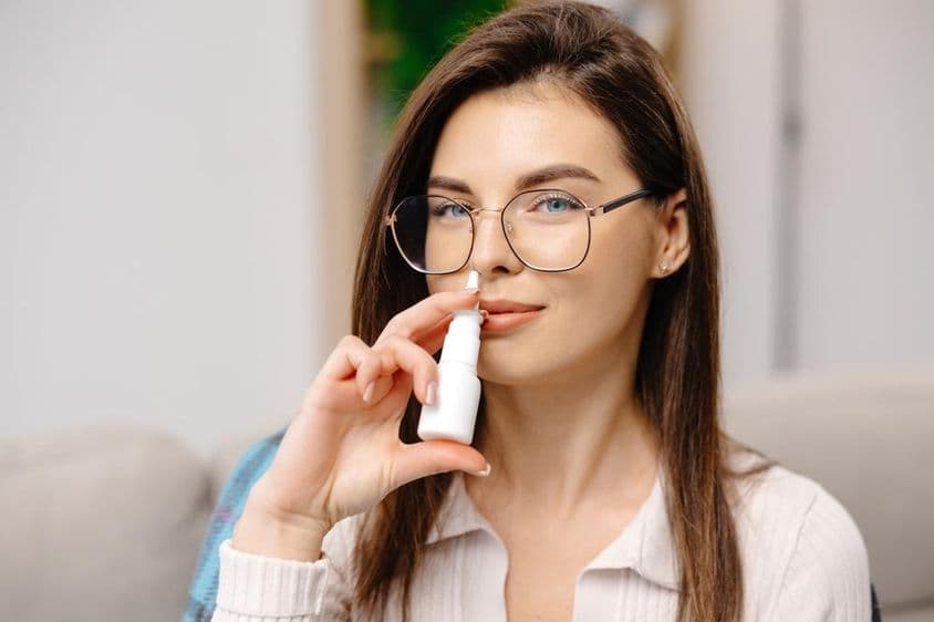 Jeune femme utilisant un spray nasal pour faciliter la respiration.