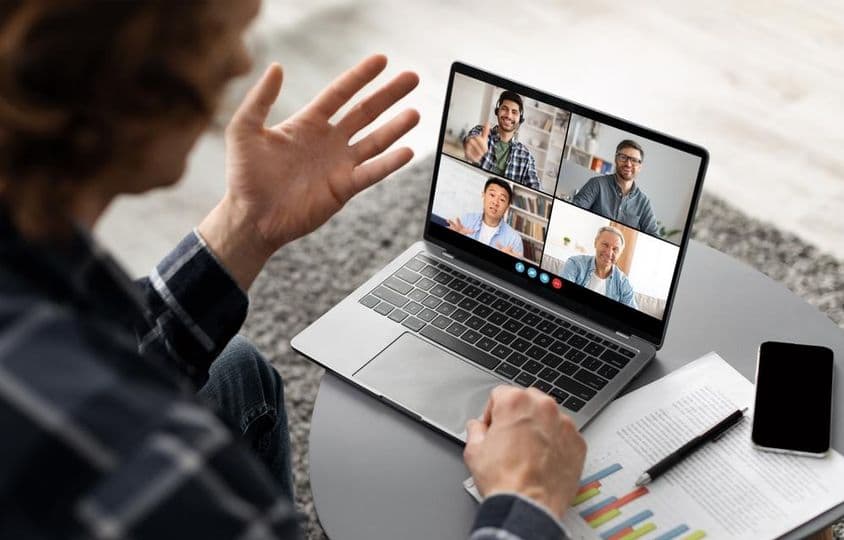 Un homme assis à un bureau, participant à une vidéoconférence sur son ordinateur portable.