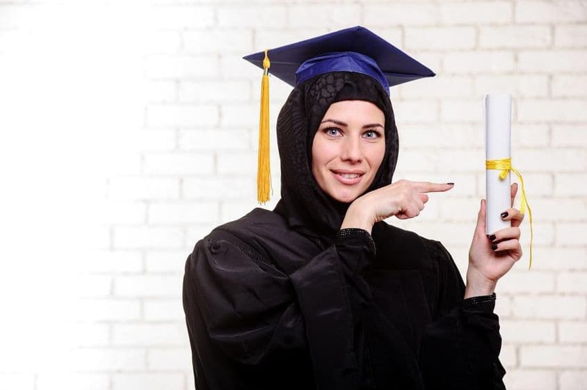 Diplômé musulman heureux posant avec un diplôme à l'intérieur.