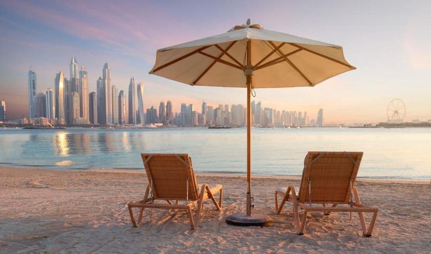 Belle plage à Dubaï avec 2 transats et un parasol.