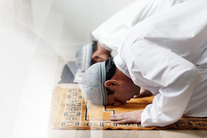 Des hommes islamiques vêtus de blanc s'inclinant en prière.