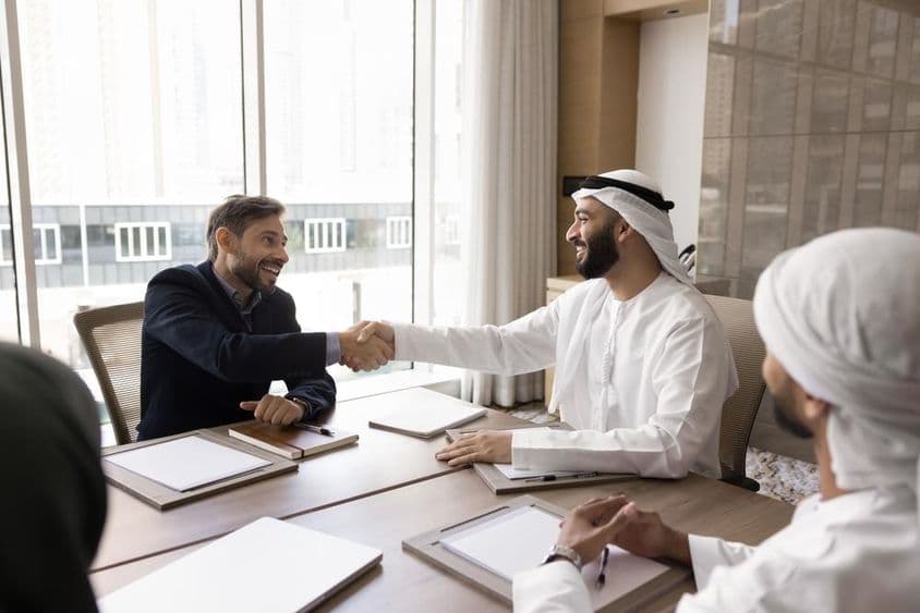 Partenaires commerciaux multinationaux concluant une négociation réussie avec une poignée de main.