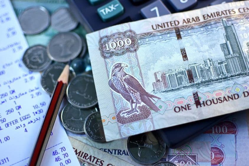 Billet de 1000 dirhams des Émirats arabes unis et poignée de pièces.