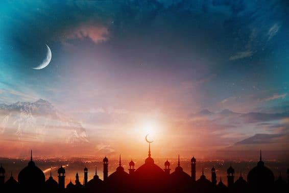 Dômes de mosquée contre un ciel bleu crépusculaire avec un croissant de lune en arrière-plan.